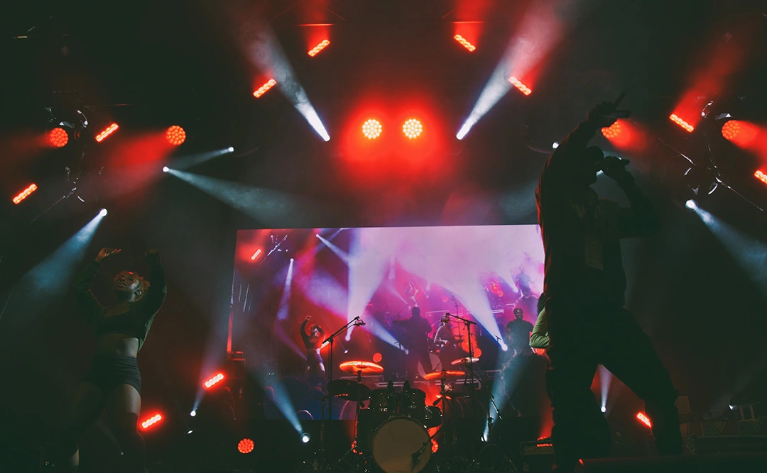 An Afrofest band performs onstage with red lighting and a large video wall