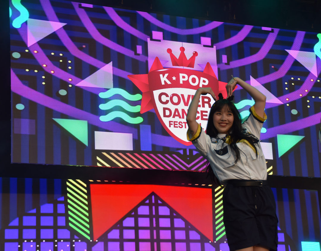 A contestant for the K-Pop cover dance festival performs onstage with two large LED video walls in the background